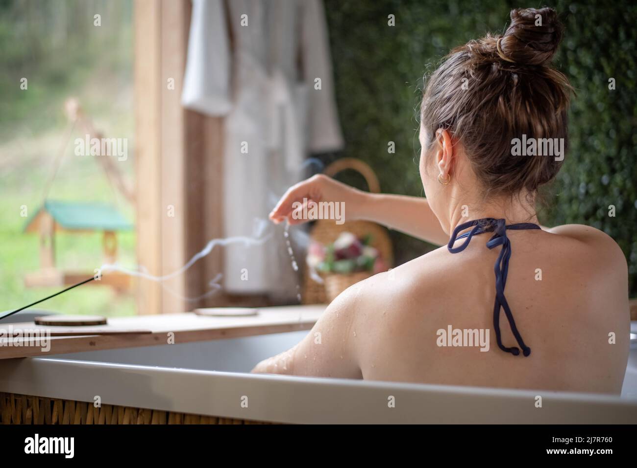 donna nella vasca idromassaggio che versa l'acqua su se stessa Foto Stock