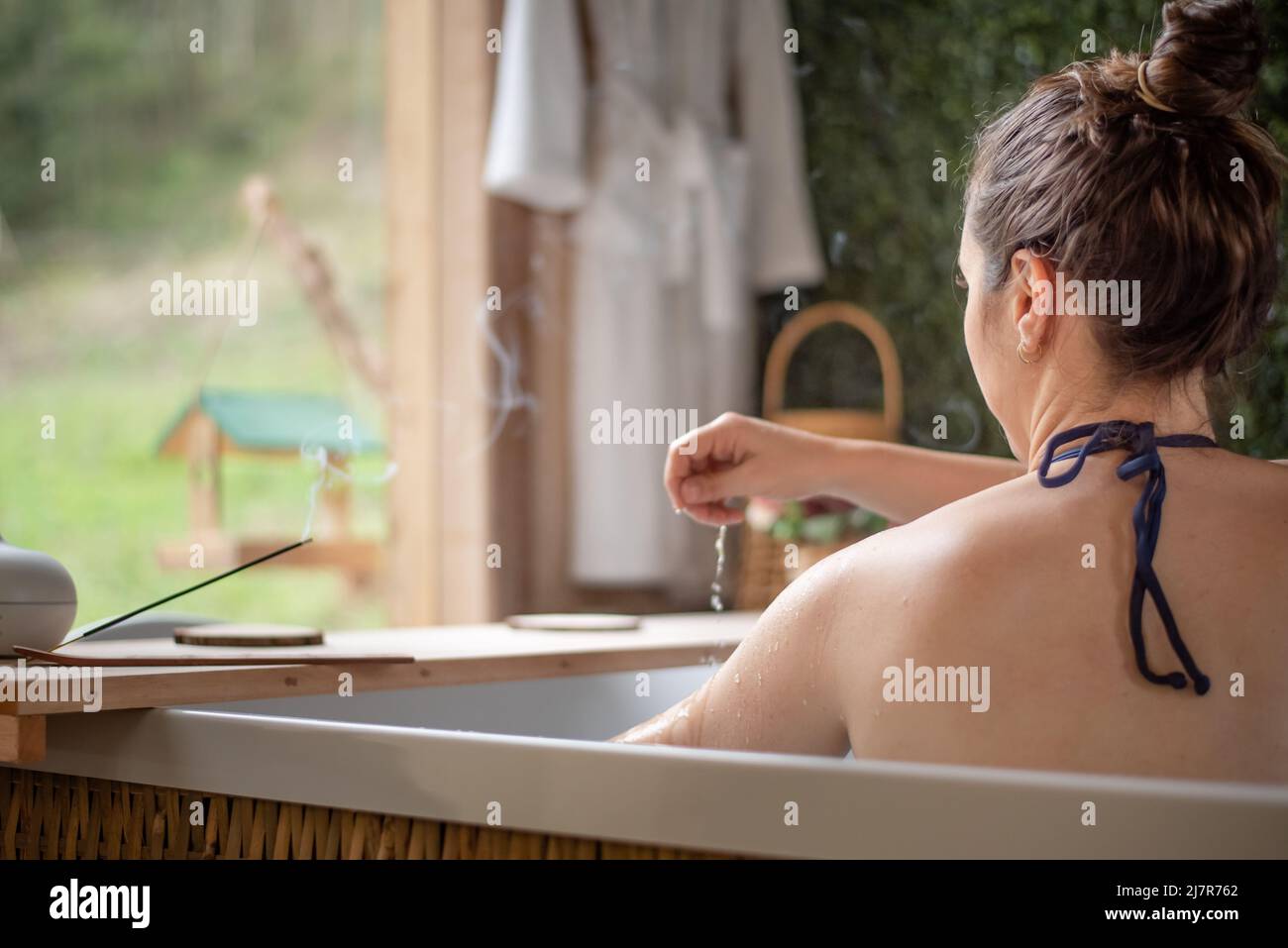 donna nella vasca idromassaggio che versa l'acqua su se stessa Foto Stock