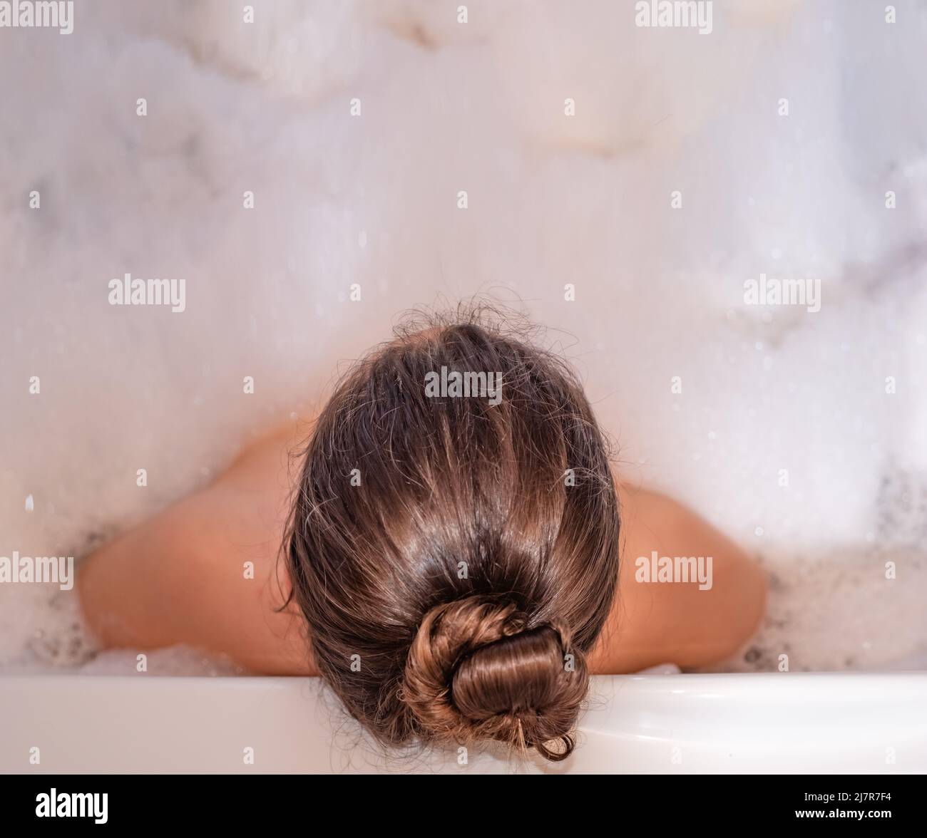 Donna che si rilassa nella vasca da bagno calda con schiuma di sapone Foto Stock