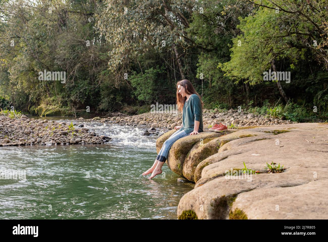 I piedi della donna penzolano dal fiume Foto Stock