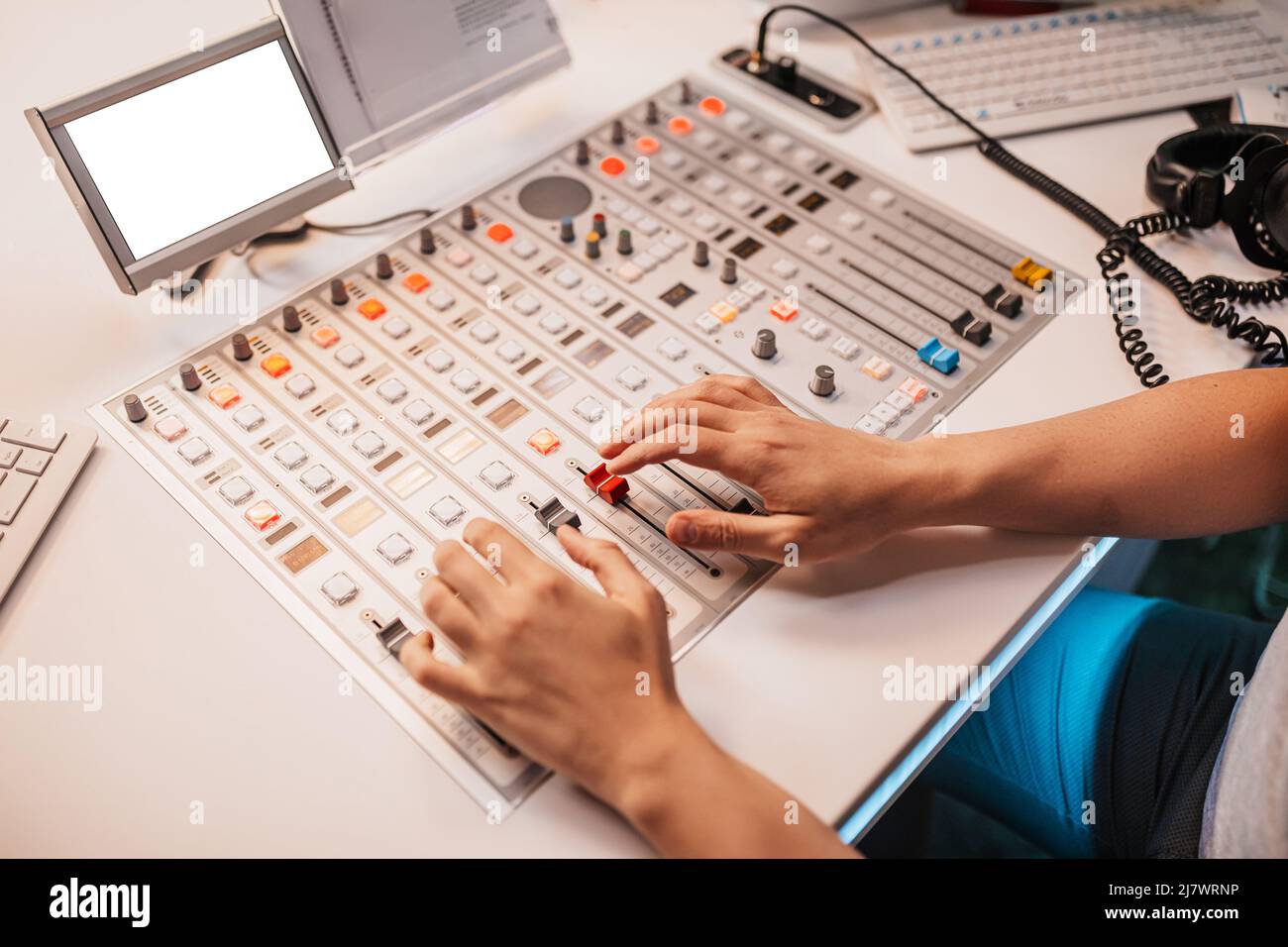 Il produttore di suoni lavora su un banco di mixaggio. Il DJ ospita il programma e comunica con il pubblico in onda alla stazione radio Foto Stock
