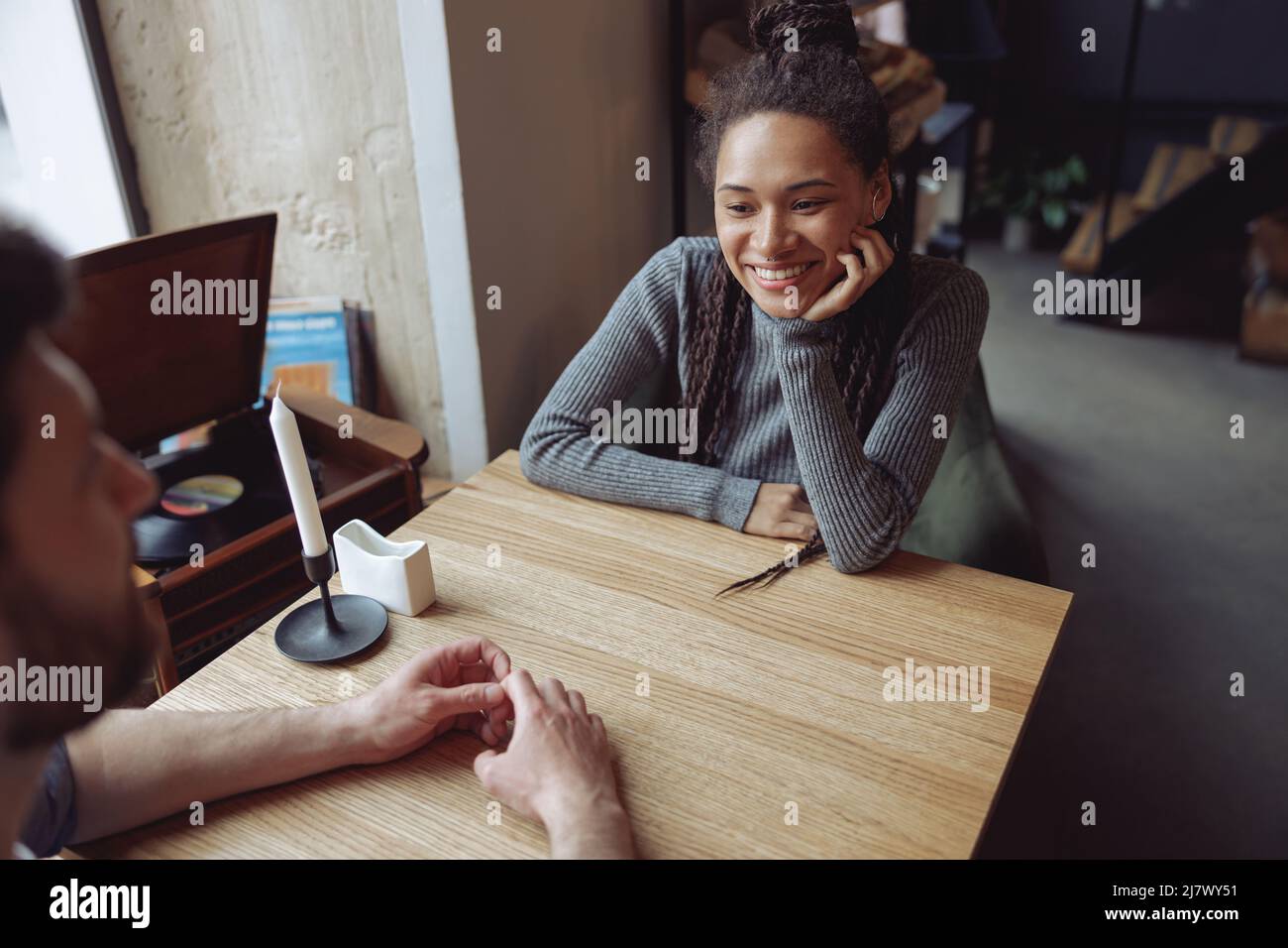 Bella giovane donna felice in amore guardando l'uomo mentre si siede al tavolo in caffetteria. Informazioni sulla data. Foto Stock
