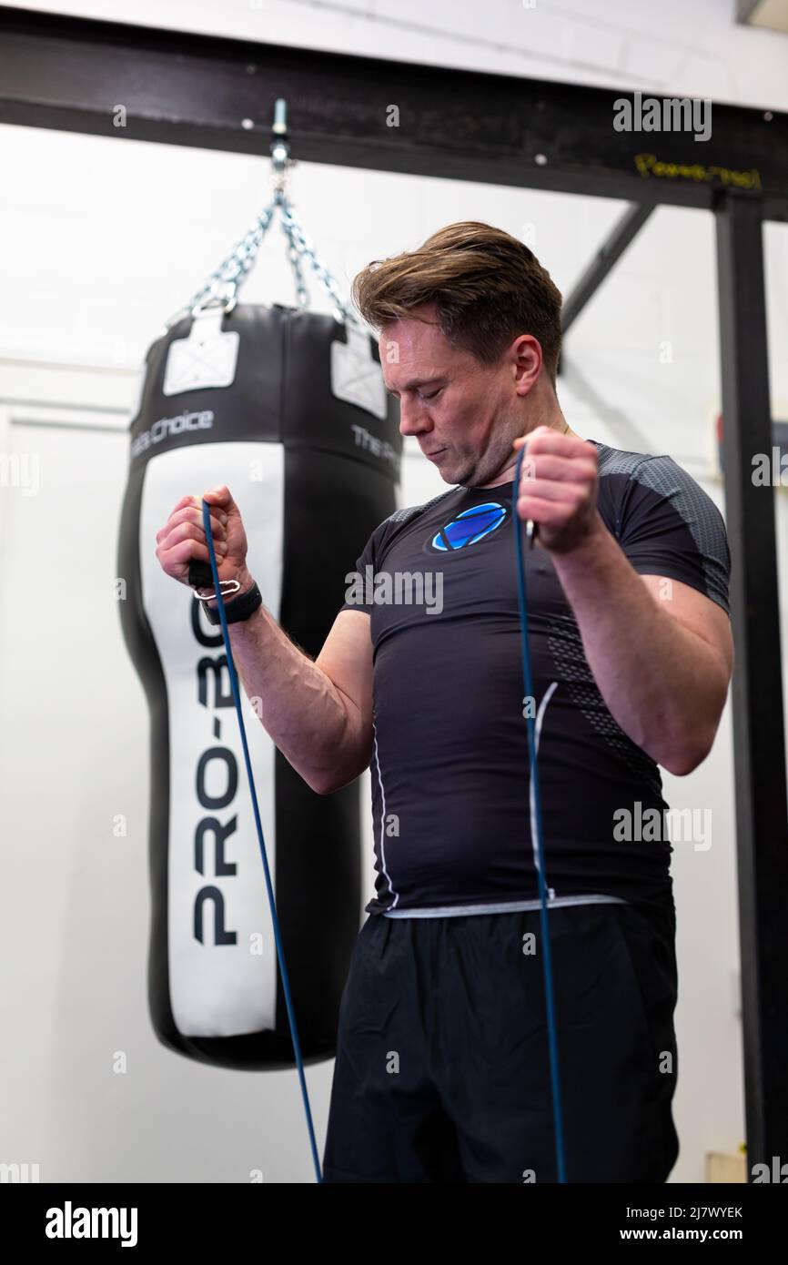Ipswich Suffolk UK Aprile 03 2022: Un uomo sano e in forma che utilizza bande di resistenza per un allenamento nella parte superiore del corpo Foto Stock