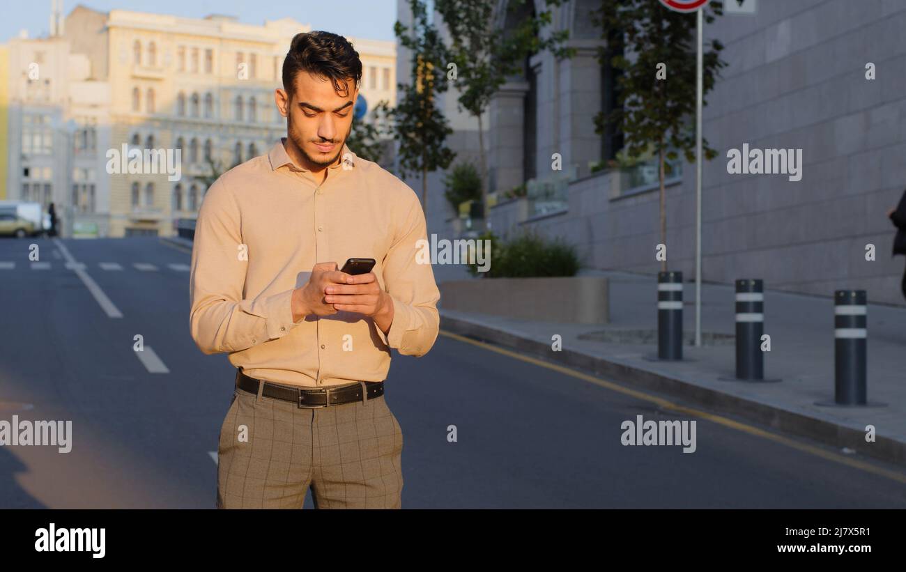 Elegante bearded ispanico businessman stand nel centro della città strada utilizza telefono cellulare SMS scorrimento tocco app tecnologia comunicazione online con Foto Stock