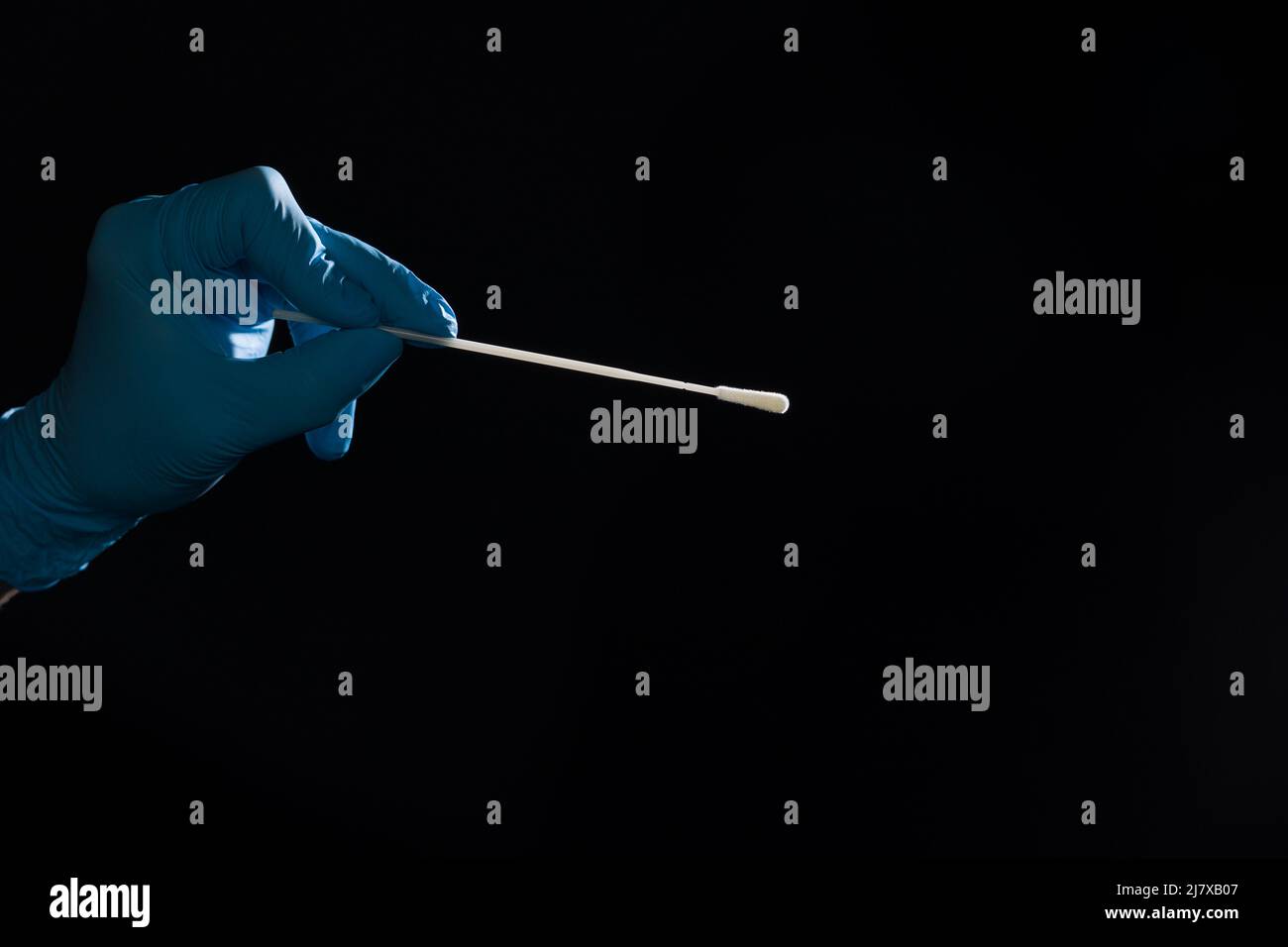 Primo piano della mano del medico che maneggia un test dello striscio o del tampone davanti ad uno sfondo nero Foto Stock