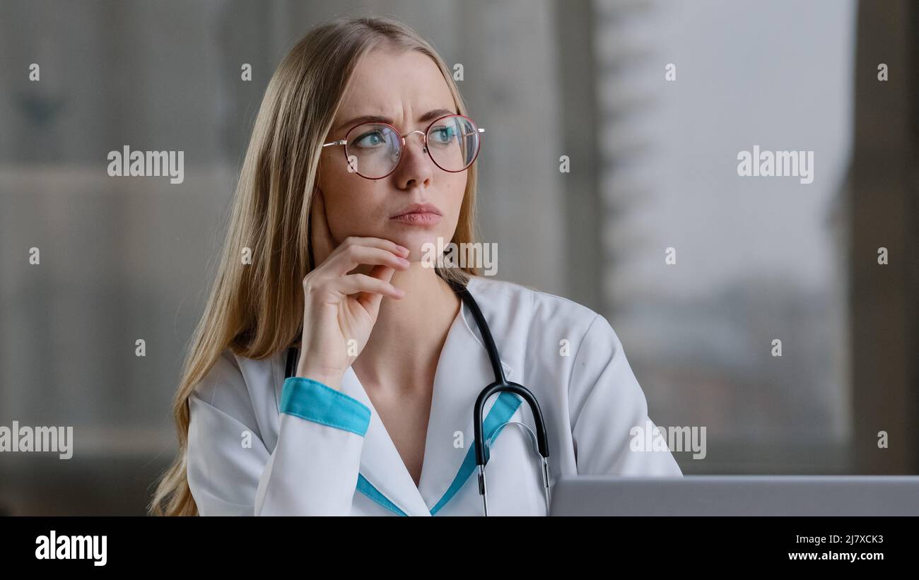 Messo a fuoco caucasico femmina psico infermiere professionista medico terapista in cappotto bianco seduto in clinica ospedale pensando di soluzione problema medico Foto Stock