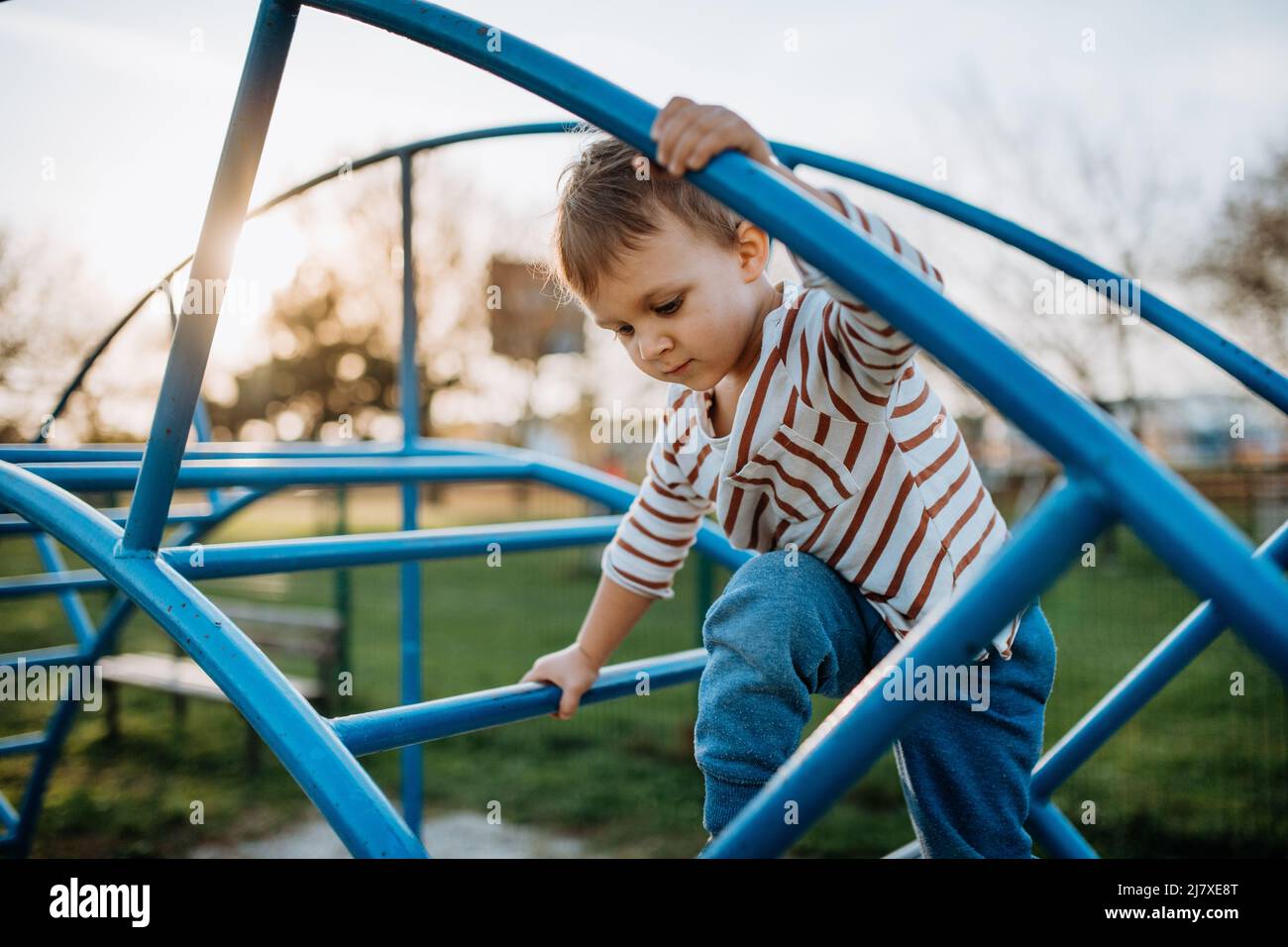 Un ragazzino che gioca nel parco giochi all'aperto. Foto Stock