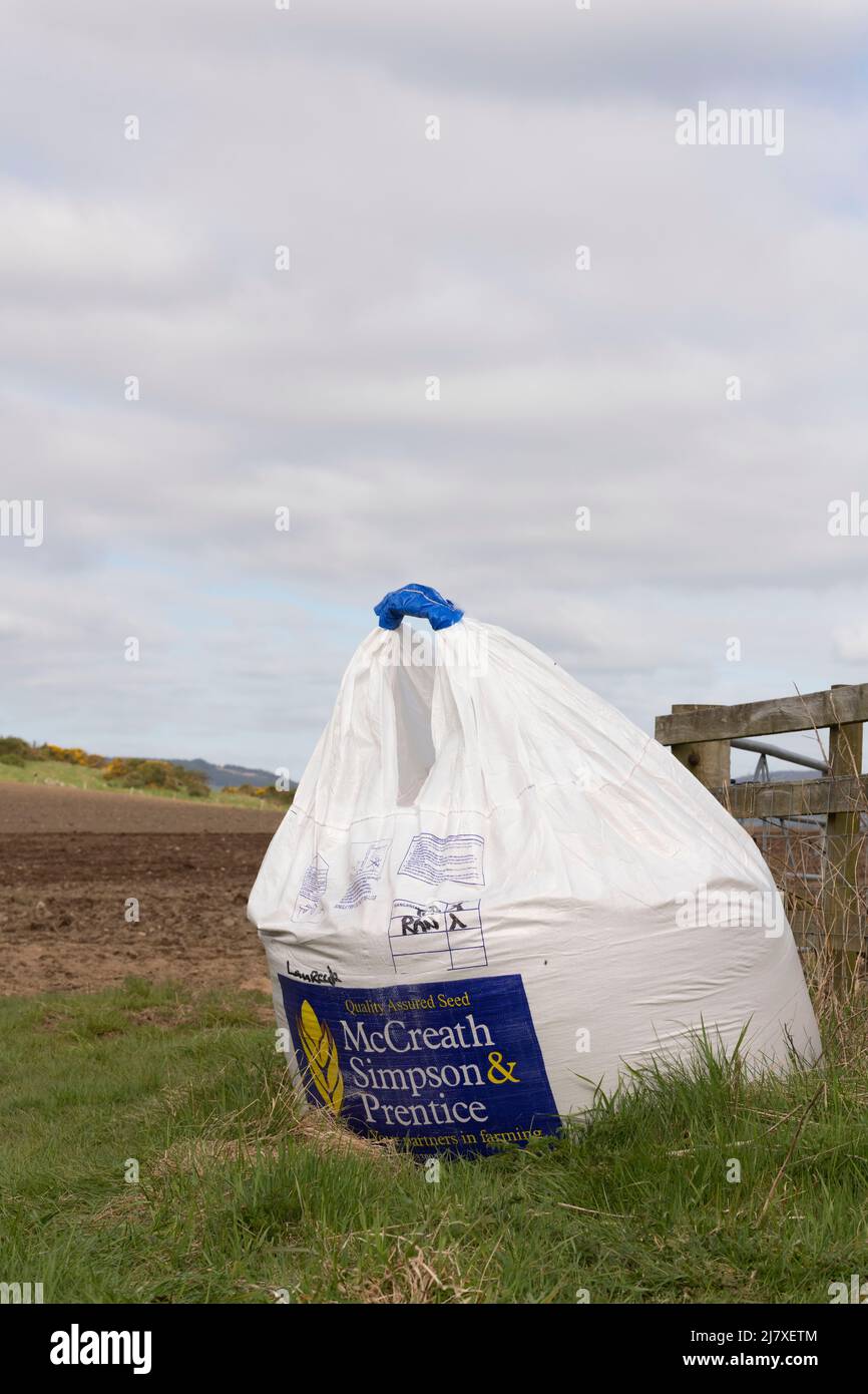 Una borsa di Barley da un mercante di semi al cancello ad un campo pronto per essere seminato. Foto Stock