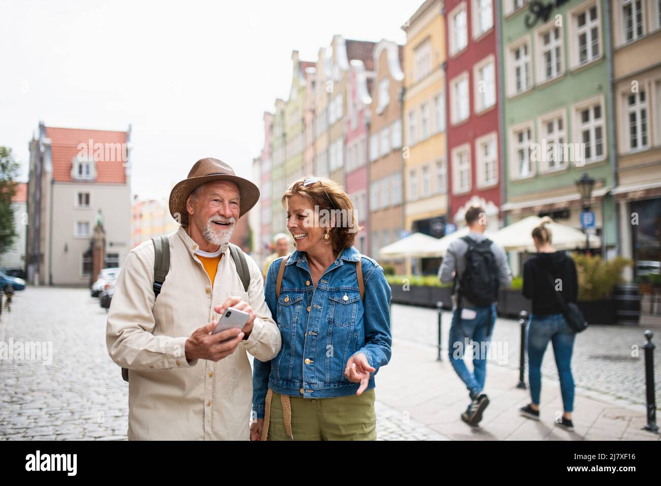 Ritratto di felice coppia di turisti che utilizzano smartphone all'aperto nella città storica Foto Stock