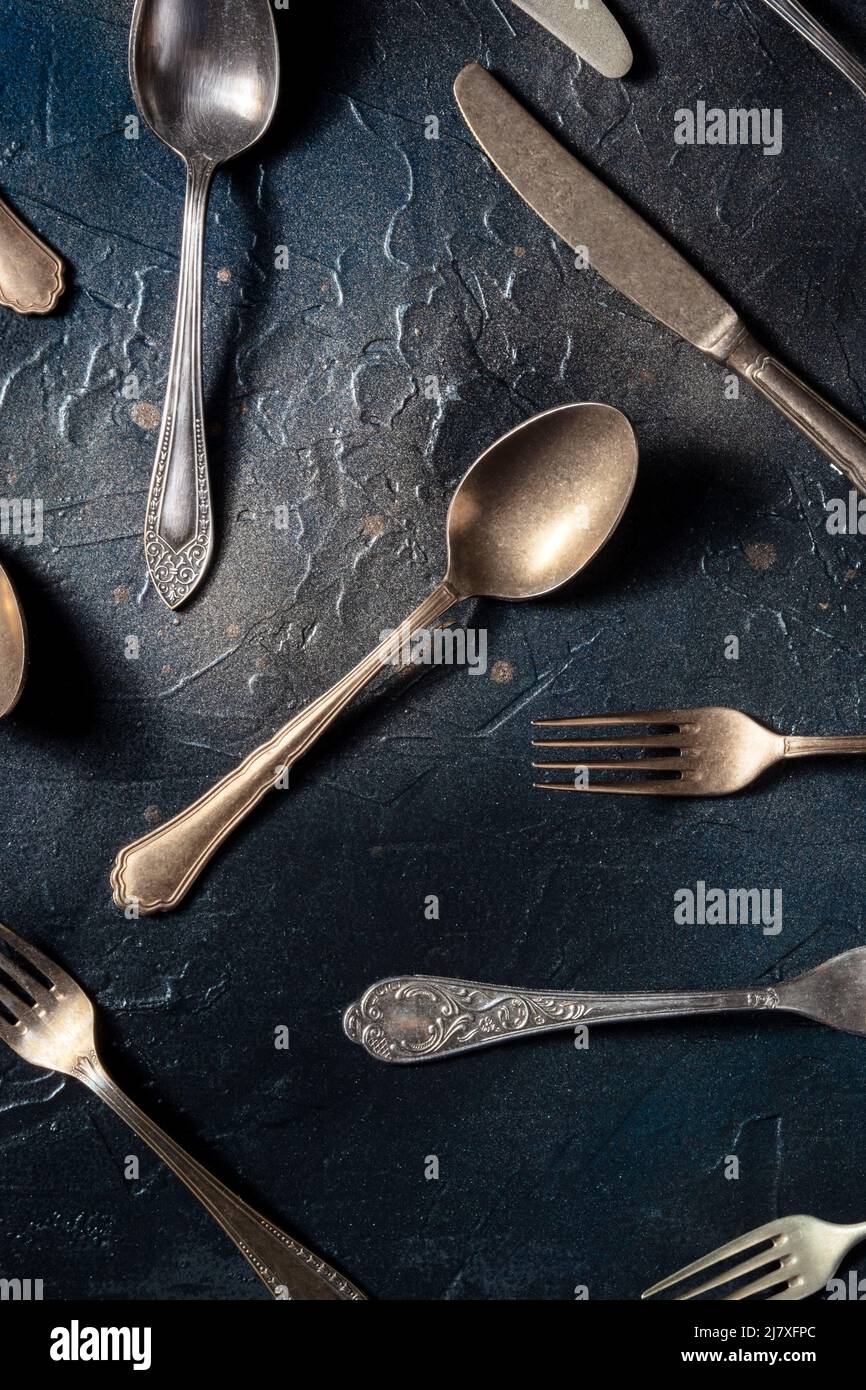 Posate piatto. Cucchiai, forchette e coltelli, vari utensili da tavola, sparati dall'alto su sfondo nero Foto Stock