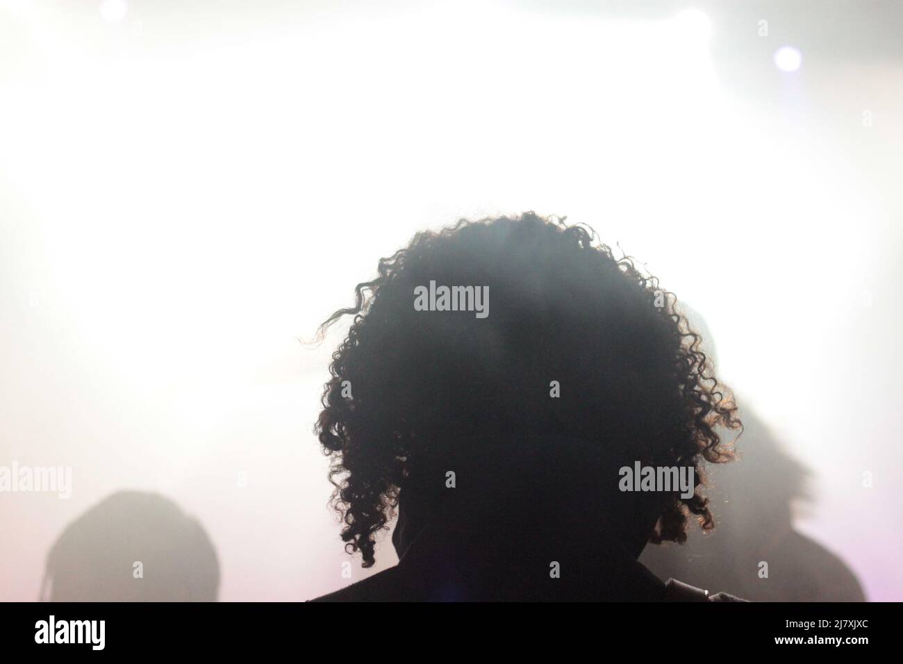 Tête d'une femme aux cheveux frisés de dos en contre-jour en pleine lumière Foto Stock