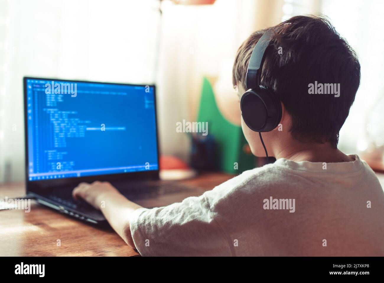 Giovane ragazzo di geek con cuffie codificate sul laptop a casa Foto Stock