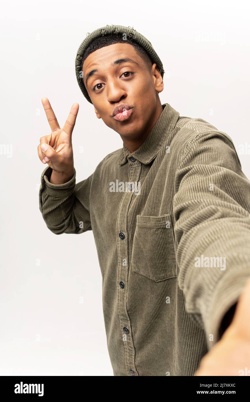 Ritratto di giovane adulto bello uomo prendendo selfie, guardando la telecamera POV e gesturing mano, punto di vista della foto. Studio interno girato isolato su sfondo bianco Foto Stock