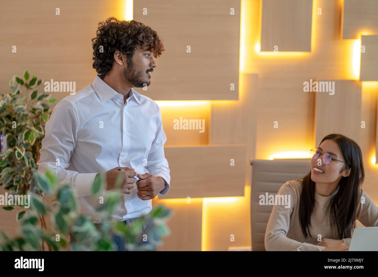 Dipendente aziendale che ha una conversazione con una collega sorridente Foto Stock