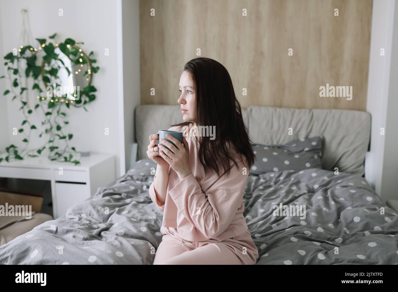 Donna positiva con cuscino seduta a letto a casa. Sogni dolci e buon concetto di mattina. Foto Stock
