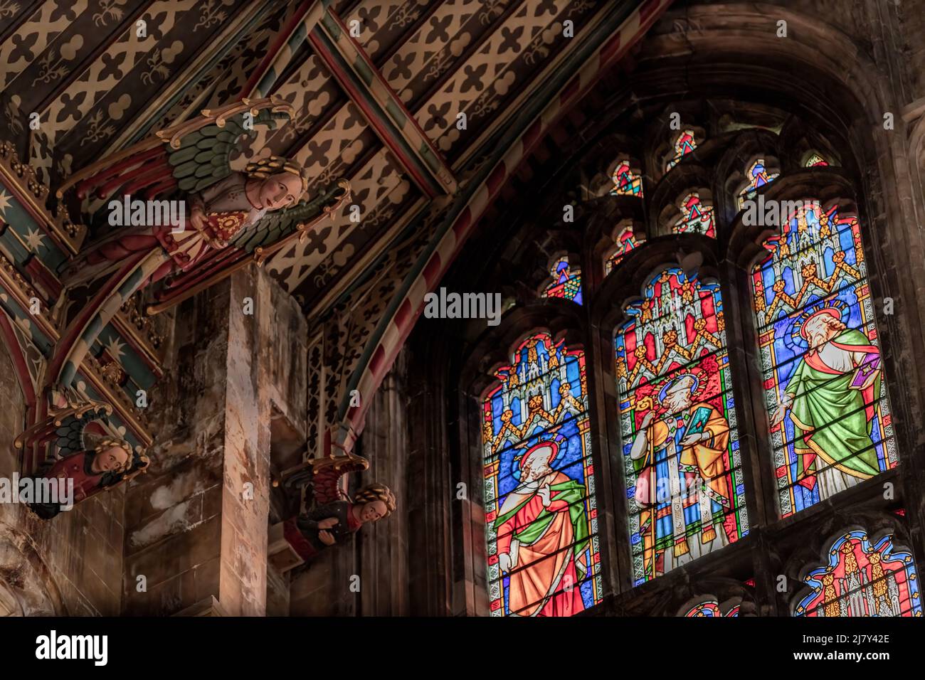 I colorati angeli di legno guardano in basso dal soffitto dipinto del transetto Nord della Cattedrale di Ely Foto Stock