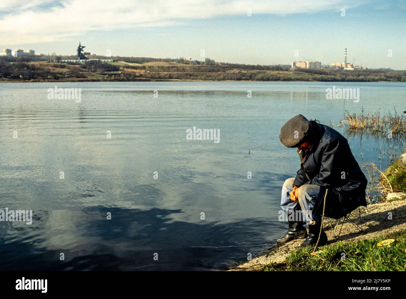 Un uomo pesca in un lago con il Monumento ai liberatori Donbas nel parco Lenin Comsomol, Donetsk, sullo sfondo. È stato inaugurato il 8 maggio 1984 ed è il monumento più grande nel sud-est dell'Ucraina, ottobre 1989. Foto Stock