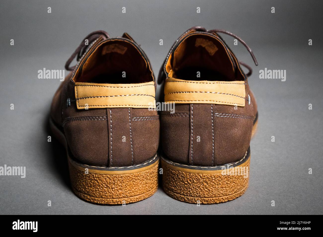 Vista laterale posteriore delle scarpe scamosciate da uomo con suole spesse e inserti in pelle su sfondo grigio Foto Stock