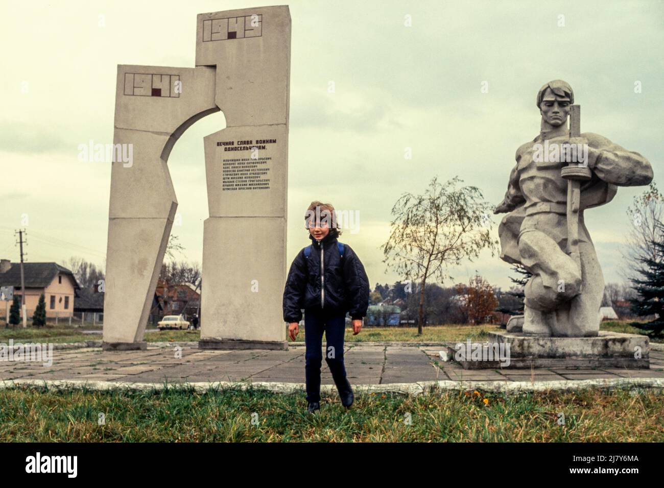 Un giovane ragazzo cammina davanti a un monumento sovietico del WW2 in un piccolo villaggio fuori Lviv nell'Ucraina occidentale. Foto Stock