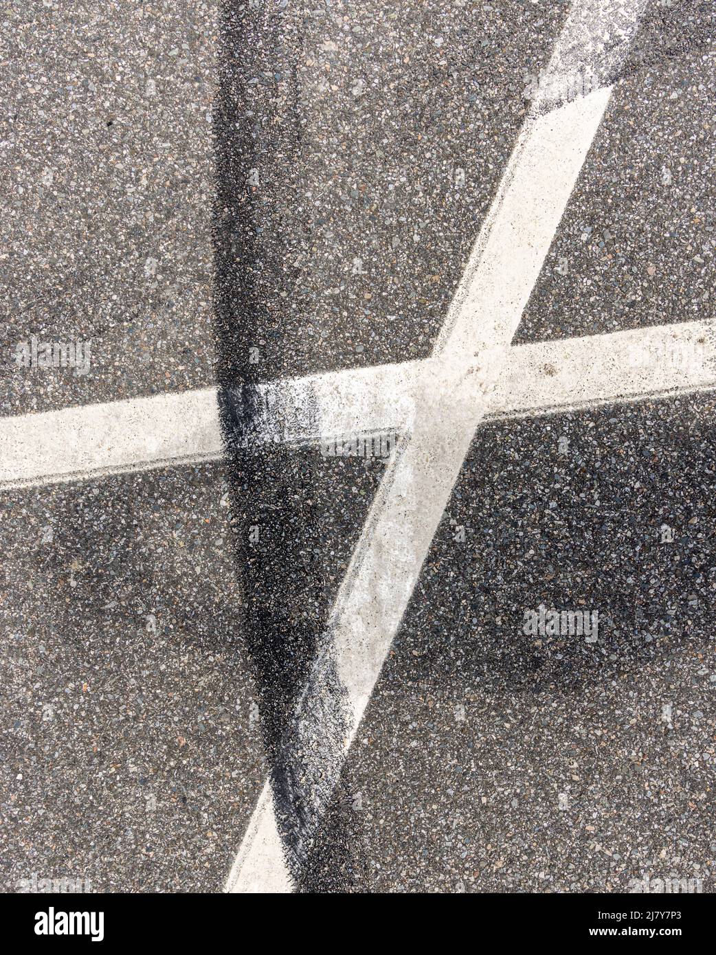 Immagine dettagliata di un contrassegno di gomma nera su linee dipinte di bianco in un parcheggio Foto Stock