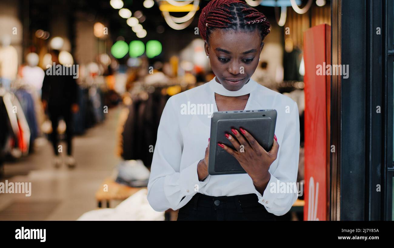 African american serio venditore di successo donna consulente in negozio di abbigliamento shopkeeper boutique dipendente guarda digitale tablet fa inventario Foto Stock