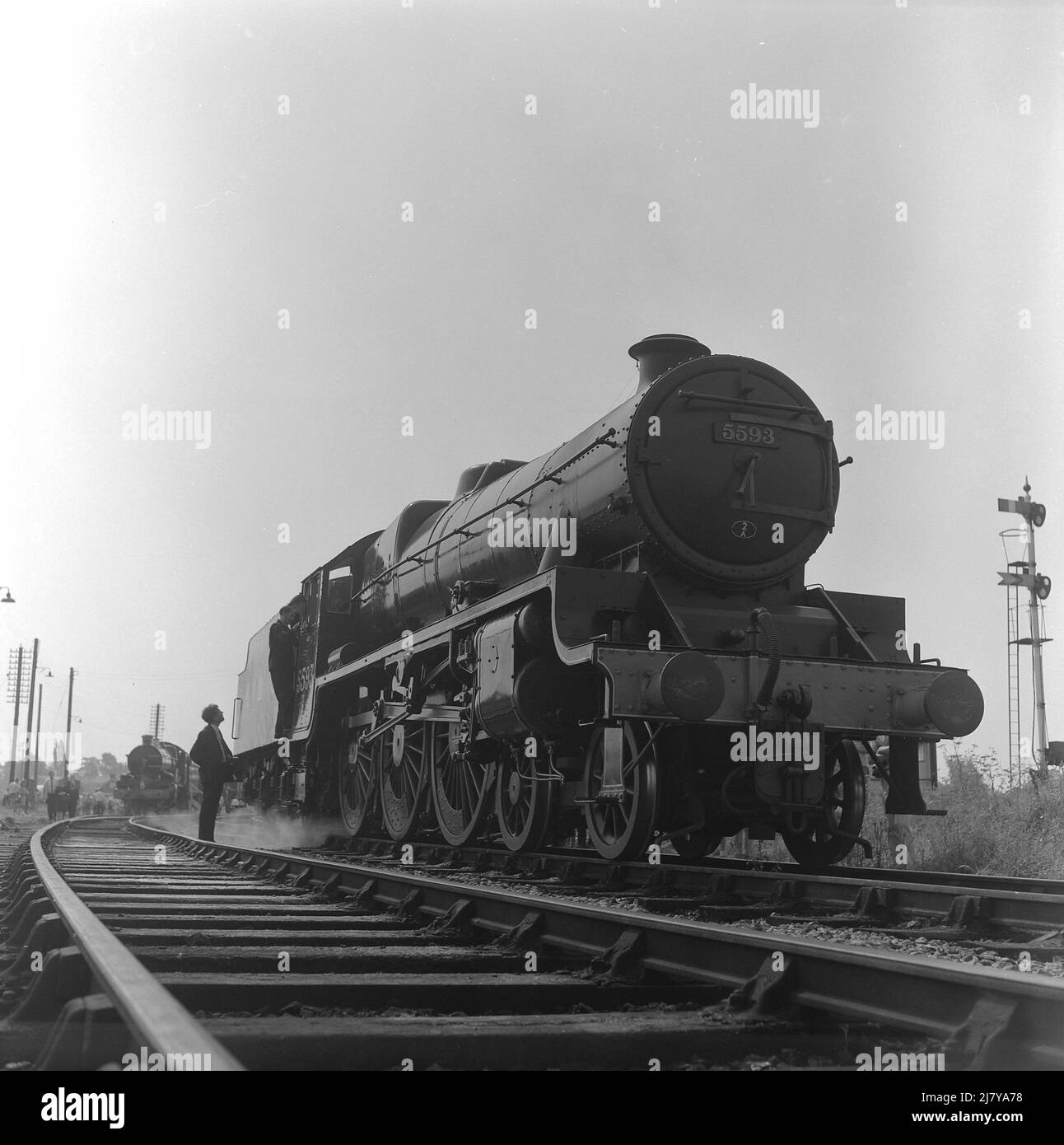 1969, storico, uomo in pista parlando con i piloti della locomotiva a vapore in attesa, KOLHAPUR 5593 LMS, Inghilterra, Regno Unito. Costruito nel 1934 dalla North British Locomotiva Company di Glasgow, è stato chiamato dopo Kolhapur nell'India occidentale nel 1936. Foto Stock