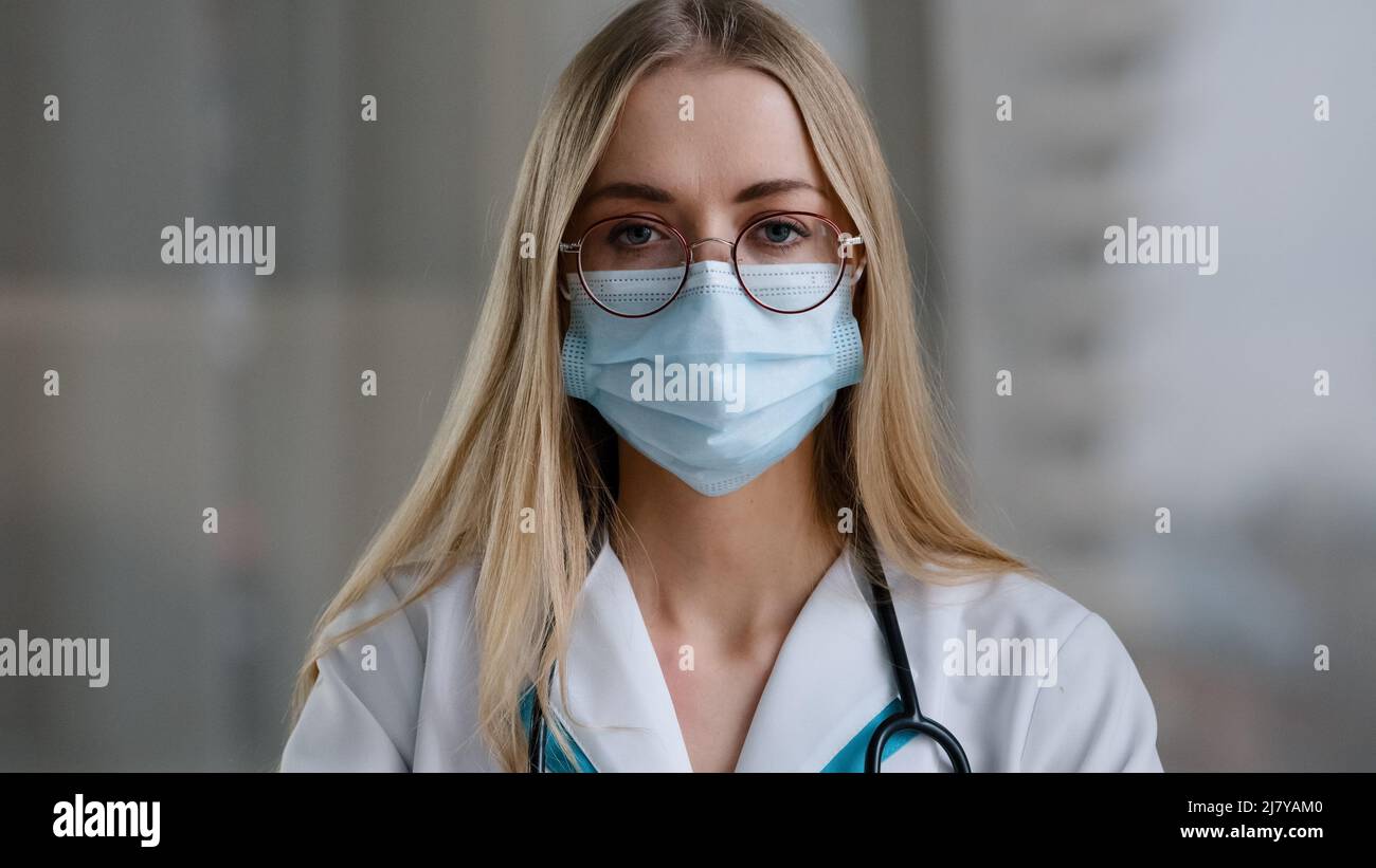 Medico femminile in maschera medica guardando la fotocamera parlare arrabbiato mostra indice dito no negativo gesto pazzo donna stressato psicologo infermiere in bianco Foto Stock