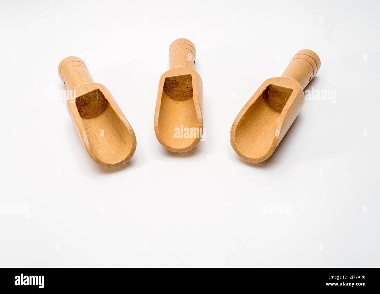 Fuoco selezionato piccole palette di legno di bambù per misurare e versare gli ingredienti su uno sfondo bianco Foto Stock