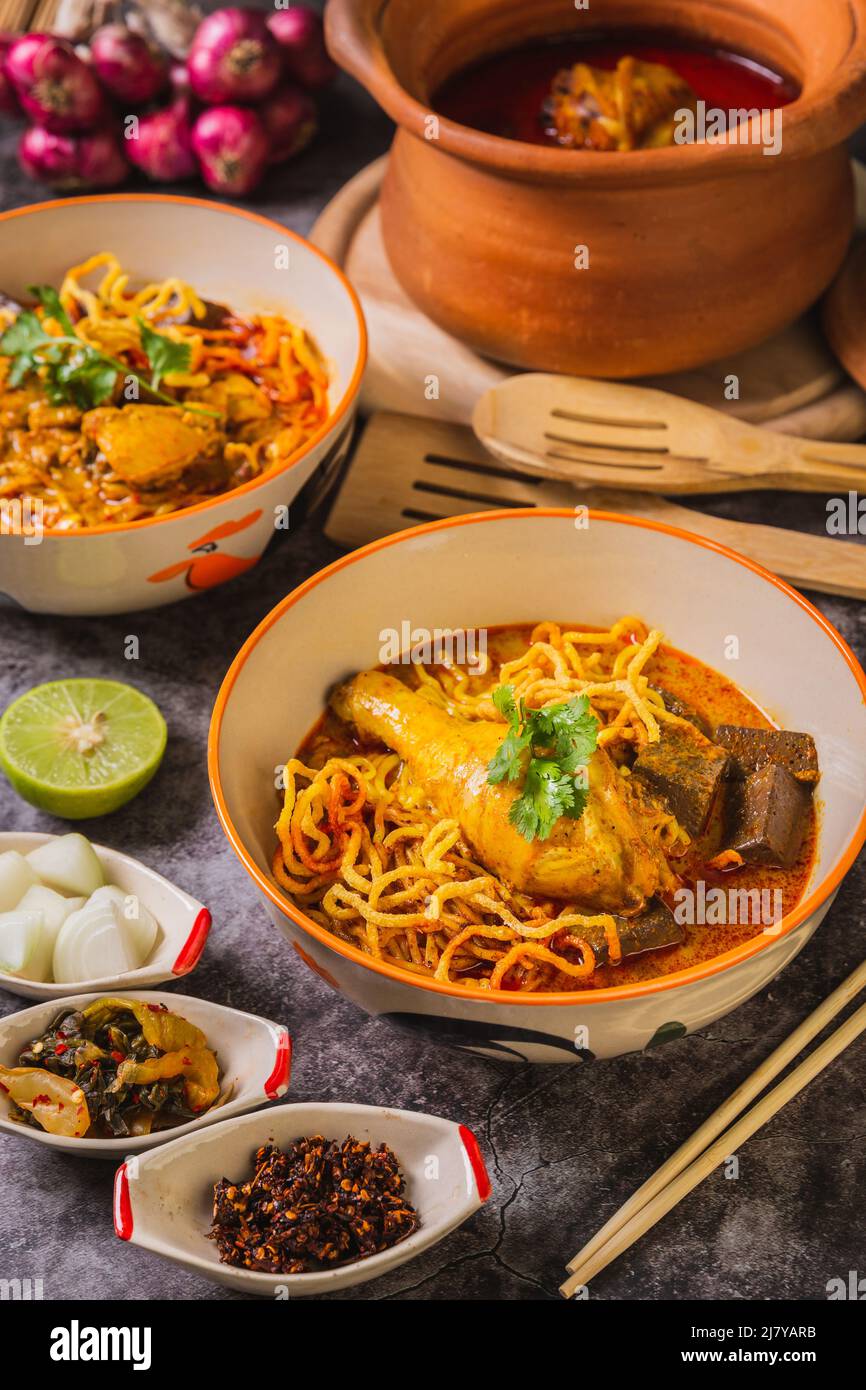 Khao Soi Kai, delizioso cibo tailandese settentrionale, organizzato con condimenti sul tavolo. Foto Stock