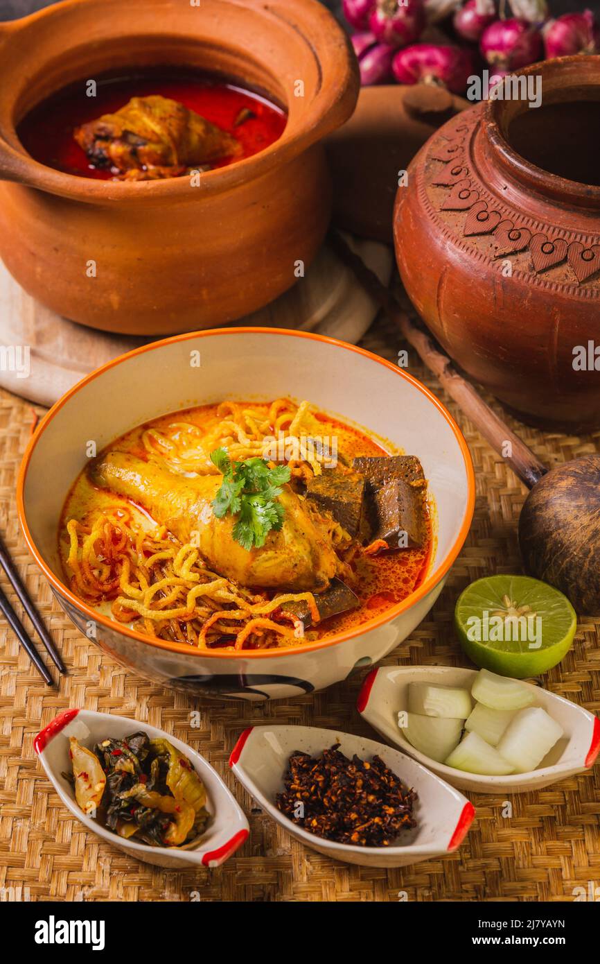 Khao Soi Kai, delizioso cibo tailandese settentrionale, organizzato con condimenti sul tavolo. Foto Stock