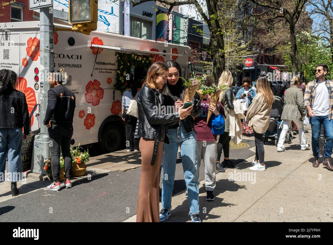 Le donne con i loro fiori ambiti dopo l'attesa in linea per ricevere un bouquet libero da Coach, a Soho a New York il sabato 30 aprile 2022. L'attivazione del marchio, alimentata dai social media, è stata una promozione per la collaborazione di Coach e ShopRunner per fornire la spedizione gratuita. (© Richard B. Levine) Foto Stock