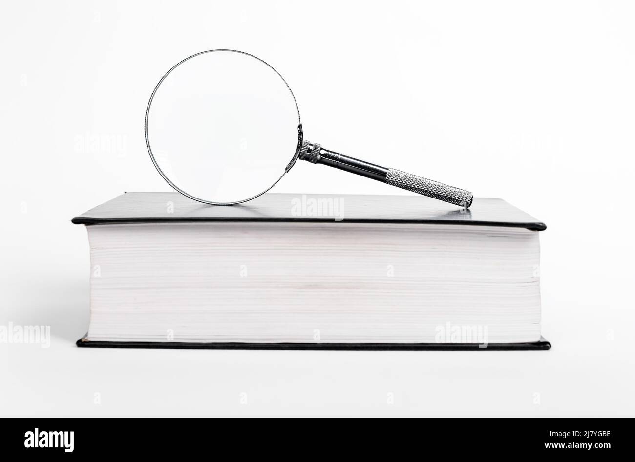 Libro con lente d'ingrandimento. Trovare e valutare informazioni per dissertazioni, progetti o relazioni. Foto di alta qualità Foto Stock