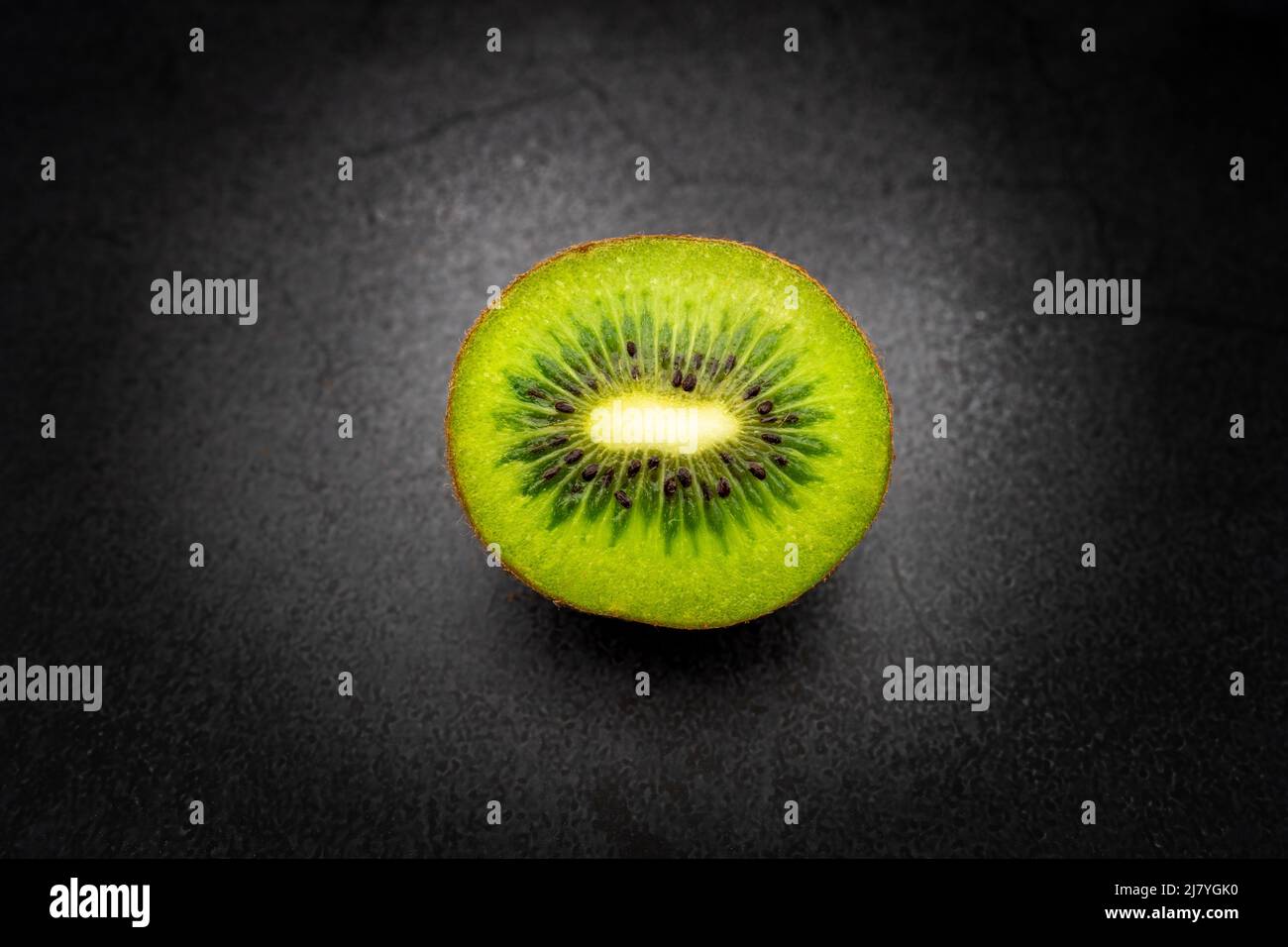 ​​half kiwi a fette isolato con sfondo scuro Foto Stock