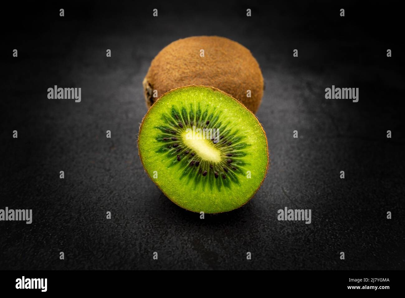 Affettato ​​half in un kiwi isolato con fondo molto scuro Foto Stock