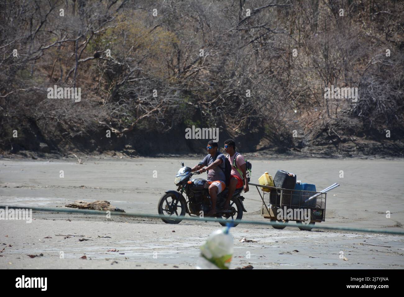 Gli uomini che spingono la barca nel surf sulla spiaggia di Costa Rica Foto Stock