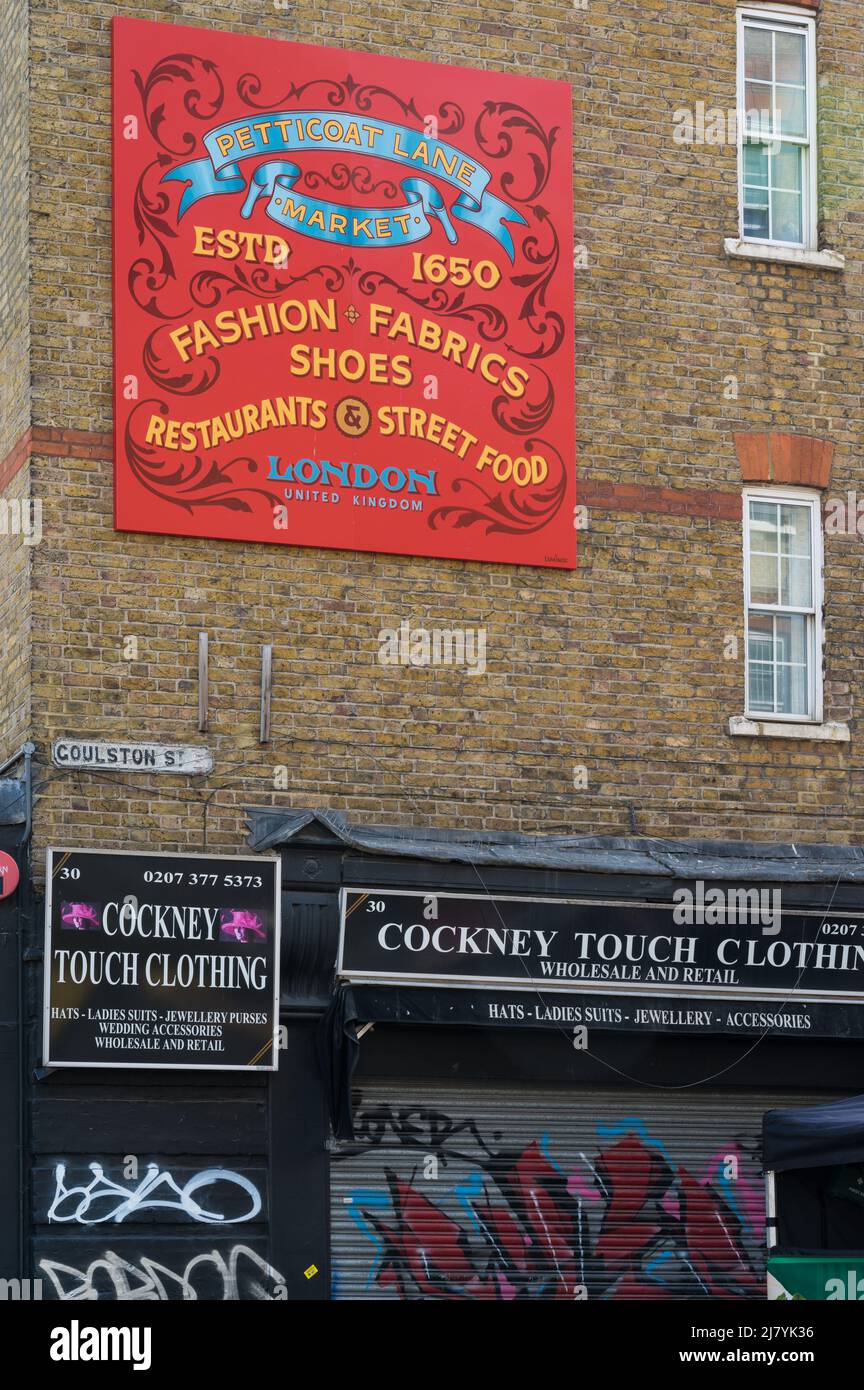 Cartello pubblicitario per Petticoat Lane Market sulla parete sopra il negozio di abbigliamento Cockney Touch in Goulston Street, Whitechapel, Londra, Inghilterra, Regno Unito Foto Stock