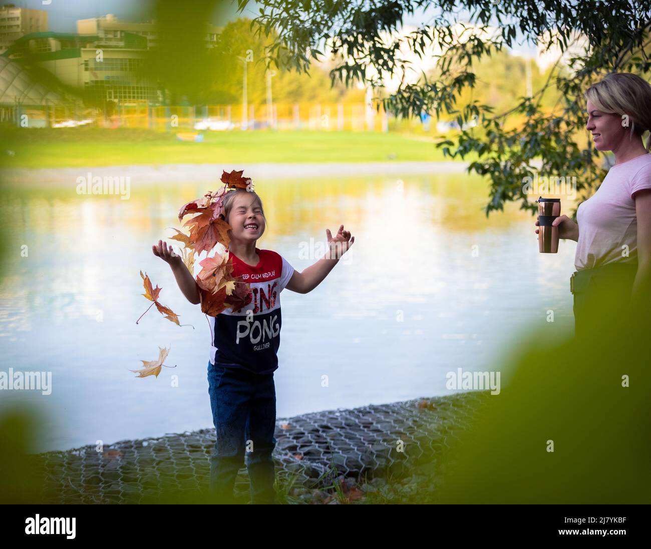 La ragazza lancia le foglie di acero colorato per una passeggiata nel parco. Foto Stock