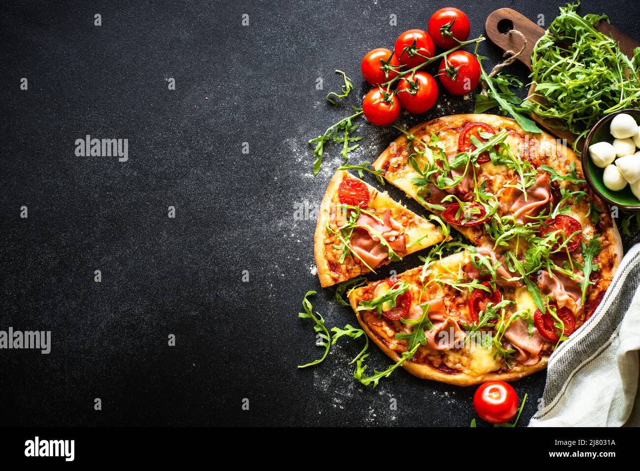 Pizza italiana tradizionale con prosciutto, formaggio, pomodori e rucola. Foto Stock