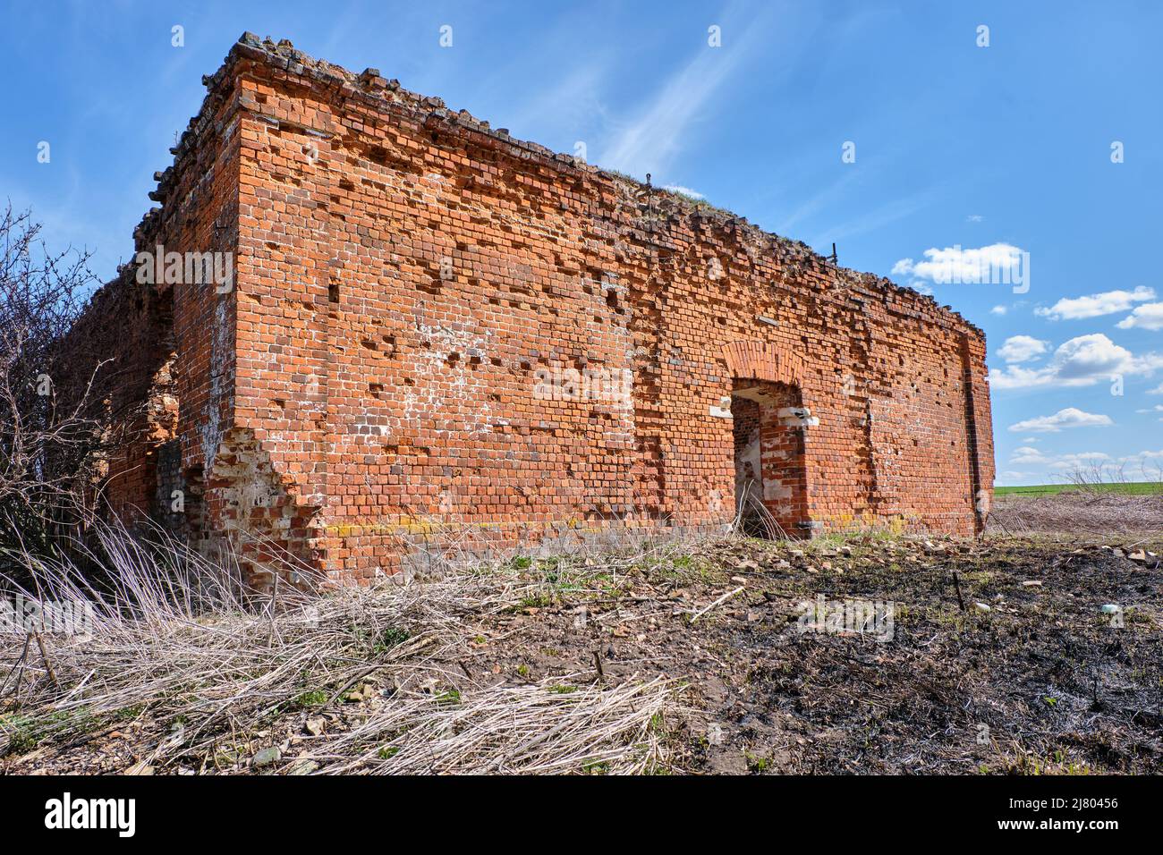 Un'antica chiesa cristiana in rovina in mattoni rossi d'estate di giorno contro un cielo blu. Foto Stock