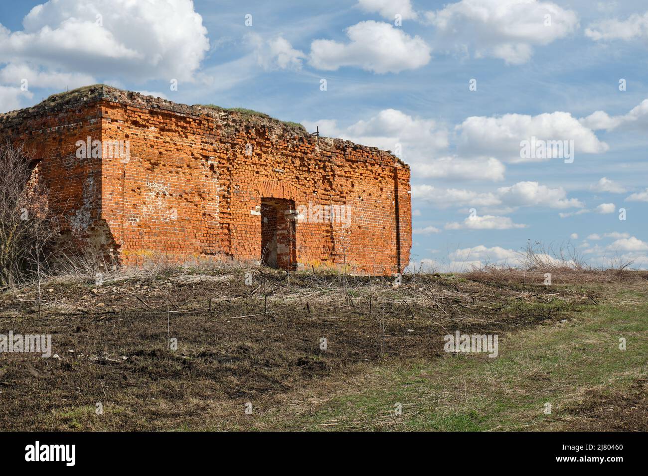 Un'antica chiesa cristiana in rovina in mattoni rossi d'estate di giorno contro un cielo blu. Foto Stock