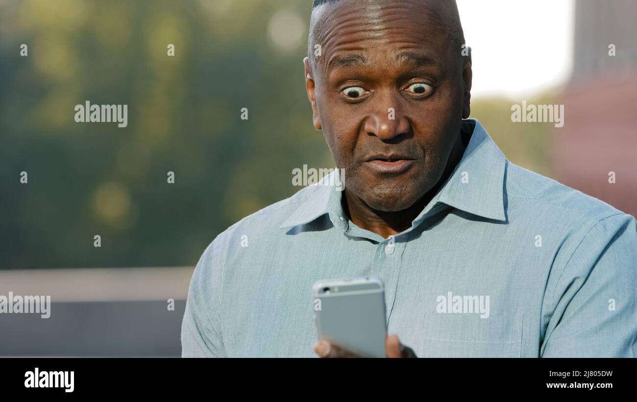 Preoccupato nervoso africano uomo tenere telefono cellulare frustrato da problemi di lamentele su cattivo servizio, arrabbiato nero persona infastidito con app mobile Foto Stock