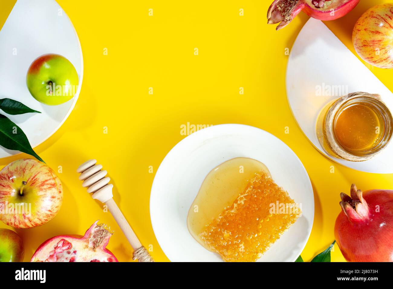 Miele, mela e melograno su sfondo giallo. Concetto ebraico Capodanno felice vacanza Rosh Hashanah. Layout creativo di simboli tradizionali. Foto Stock