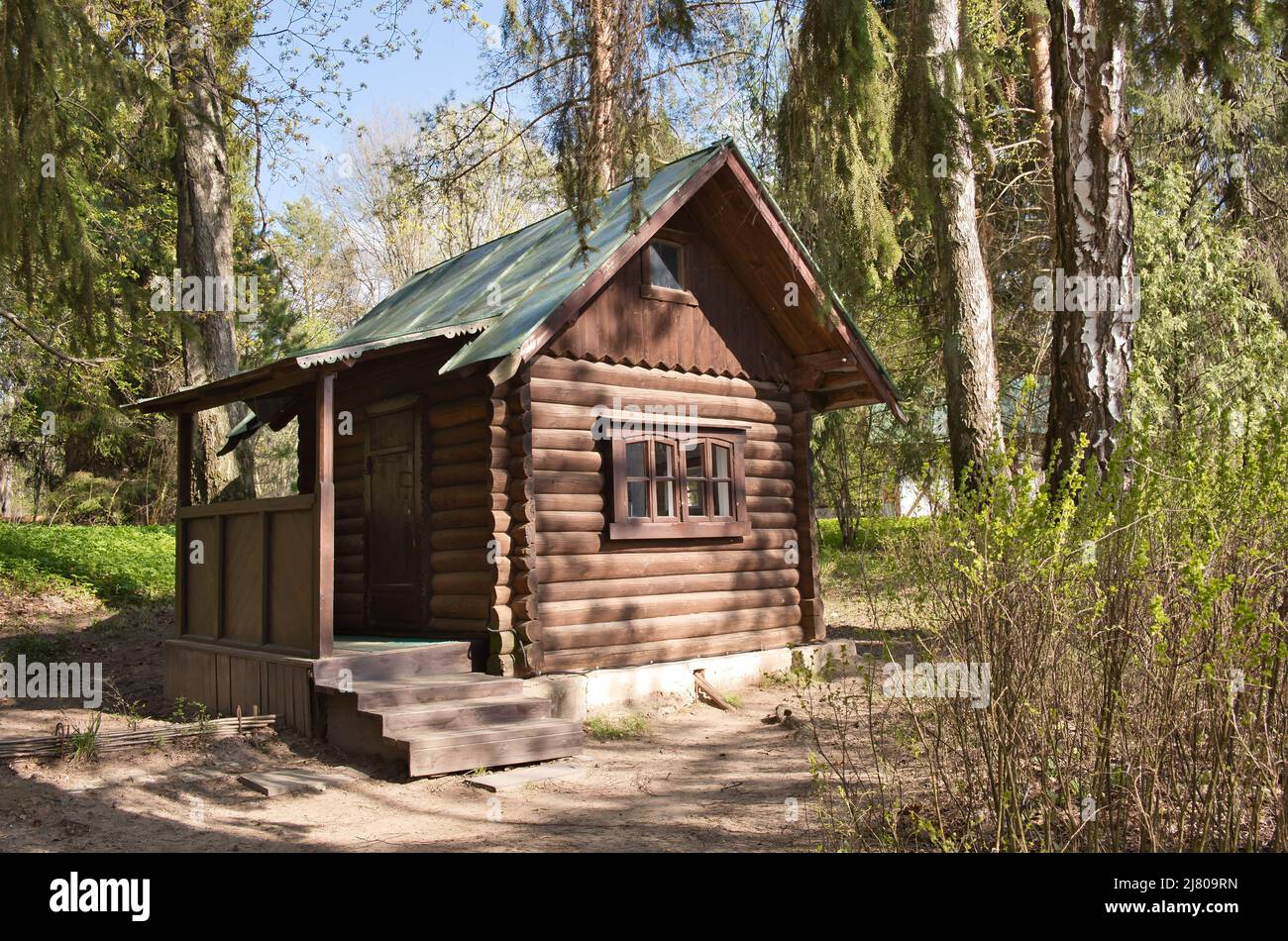 Piccola casa in legno nella foresta. Forester o capanna di legno del cacciatore tra gli alberi. Foto Stock