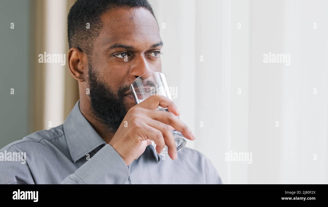 Sorridendo felice ragazzo afroamericano giovane, dipendente azienda che tiene il vetro ottenendo la bevanda di acqua fredda pura. Sana razza mista portava l'uomo idratante Foto Stock