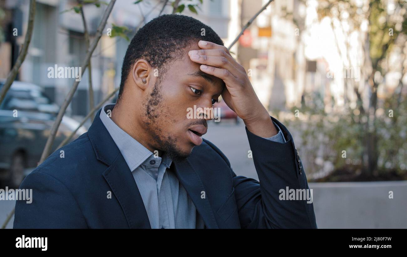 Sottolineato esausto giovane dipendente di società mista corsa che ha doloroso testa sentimenti a causa di un lavoro eccessivo computer o uno stile di vita di lavoro sedentario. Nero stanco Foto Stock
