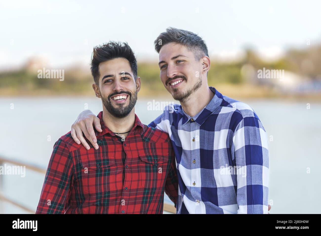 ritratto di coppia gay abbracciato da un fiume Foto Stock