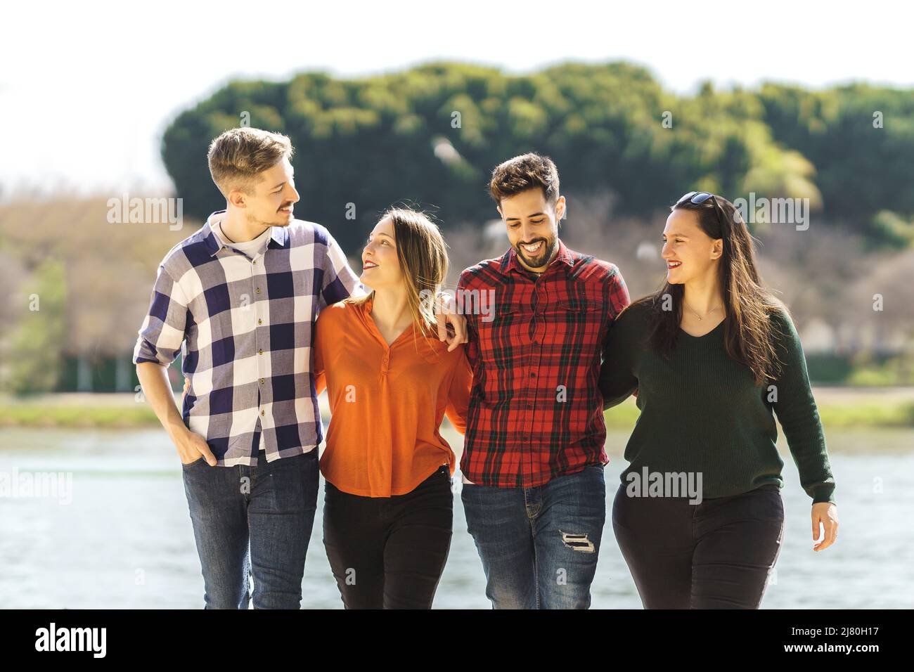 gruppo di amici che ride mentre passeggi vicino a un fiume Foto Stock