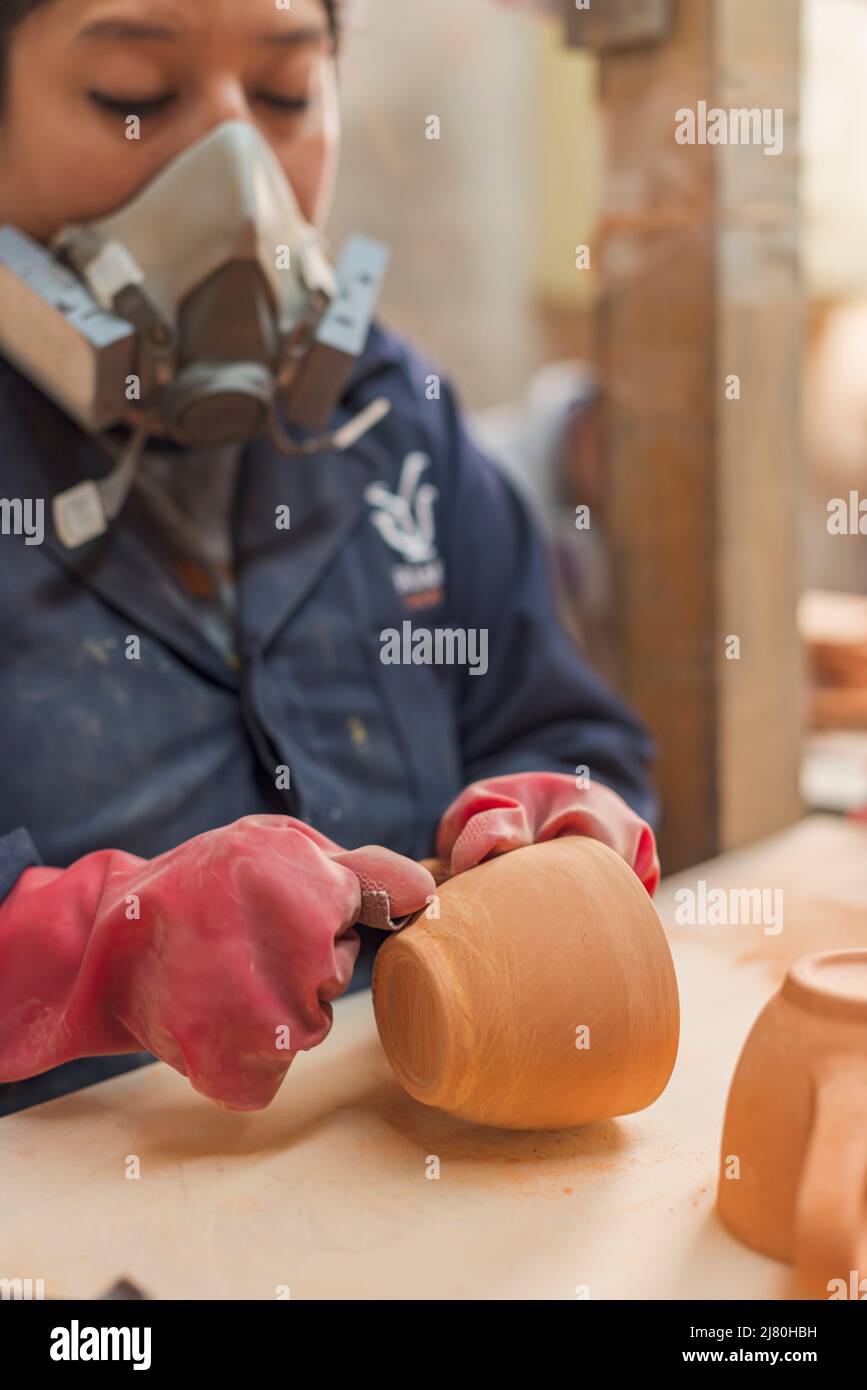 Artigiani messicani levigano una tazza di argilla in una fabbrica di talavera Foto Stock