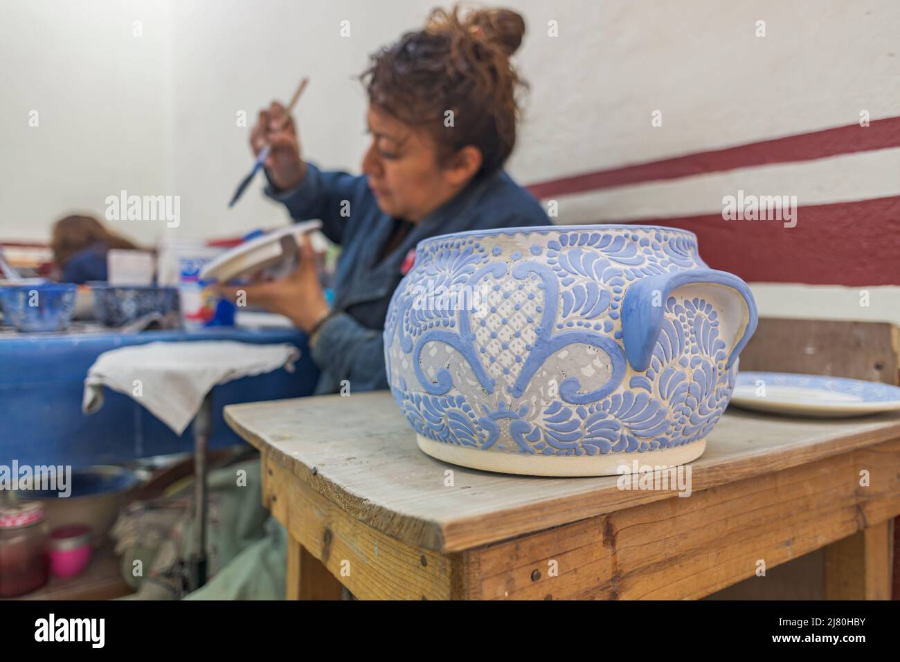 Artista messicano che dipinge modelli di talavera blu su ceramica Foto Stock