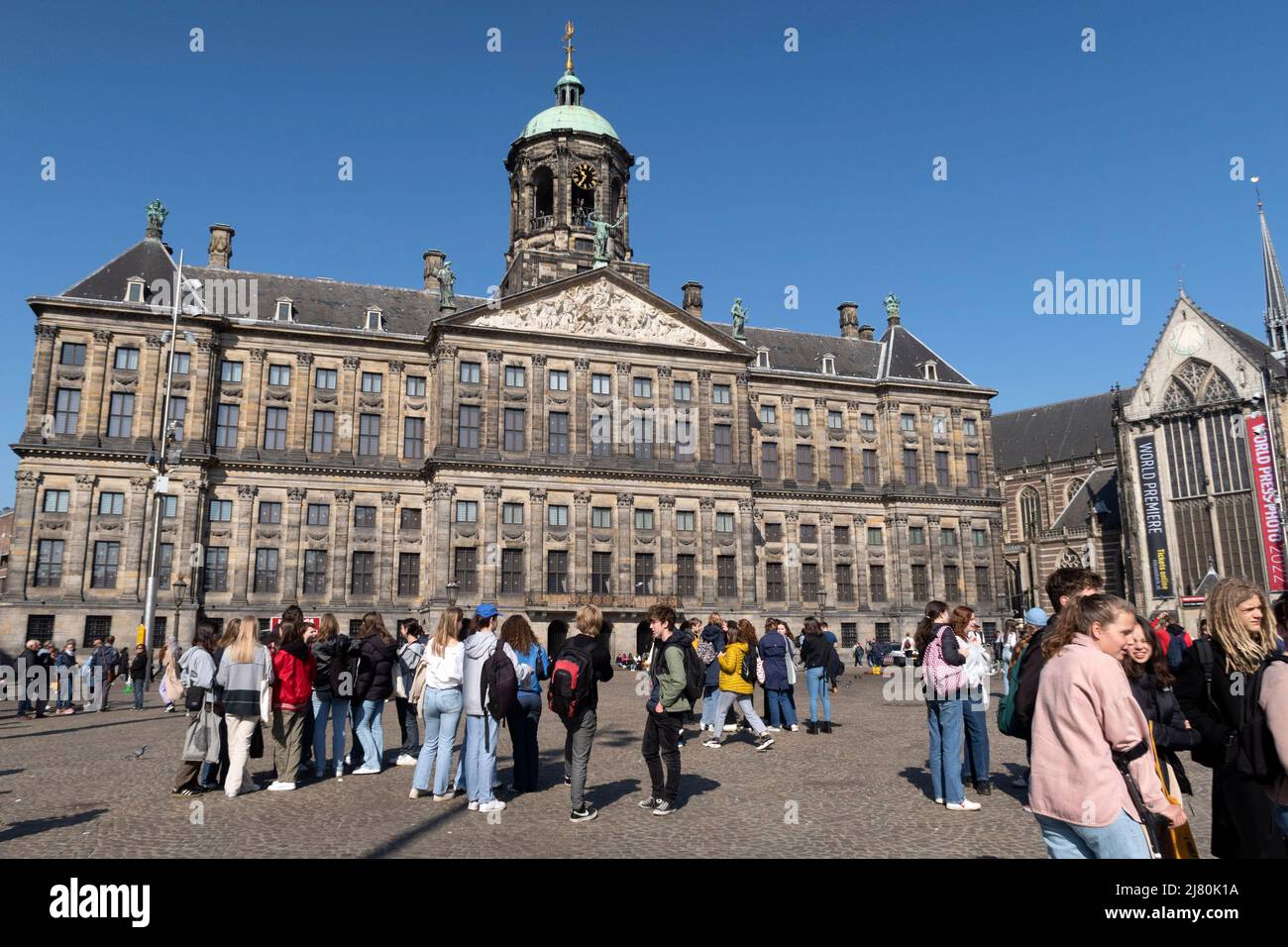 I turisti si riuniscono di fronte al Palazzo reale in Piazza Dam, sotto un cielo azzurro e limpido ad Amsterdam, Paesi Bassi Foto Stock